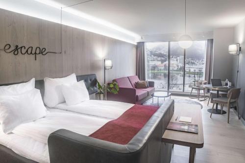 a bedroom with a large bed and a living room at Hotel Norge by Scandic in Bergen