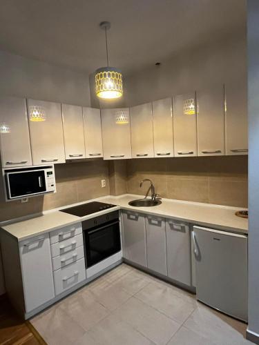 una cucina con mobili bianchi e un lavandino di Amore a Ulcinj