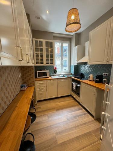 une cuisine avec des armoires blanches et un plancher en bois dans l'établissement Luxurious 2 bedroom apartment, located in Avenue George V, à Paris