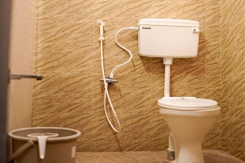 a bathroom with a toilet with a hose on the wall at H2cottage in Wodapatti
