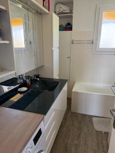 une salle de bain avec un lavabo et une baignoire dans l'établissement Appartement vue sur collines de Cannes, au Cannet