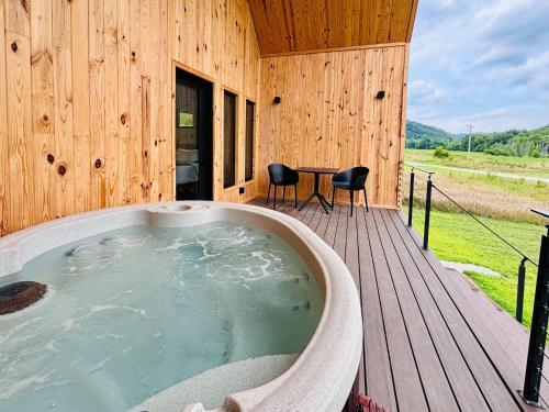 a hot tub on the deck of a wooden cabin at New! Trail Tamer | River Access | Mountain Views in Slade