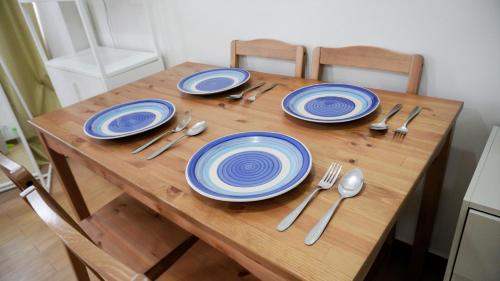 a wooden table with blue and white plates and silverware at Warm & Cozy Retreat near SM City Trece Martires in Trece Martires