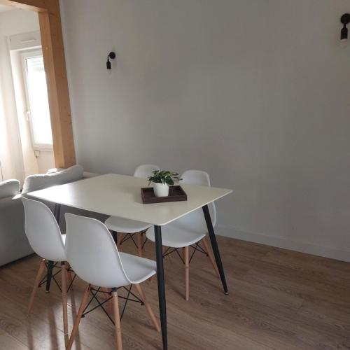 une table et des chaises blanches avec une plante. dans l'établissement Le refuge du lac, à La Tessoualle