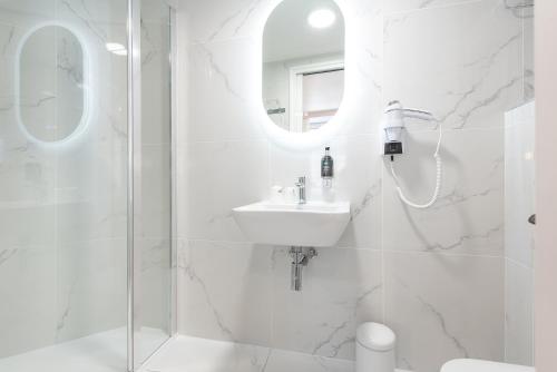 a white bathroom with a sink and a shower at Hôtel Restaurant Le Relays du Chasteau - Logis Hôtel in Brousse-le-Château