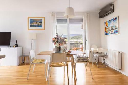 un comedor con una mesa con sillas y un jarrón de flores en Eurorail logistics Apartment, en Zagreb