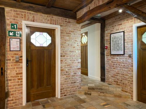 a brick hallway with a wooden door and a brick wall at Landgoed De Hoogmolen in Oudsbergen 