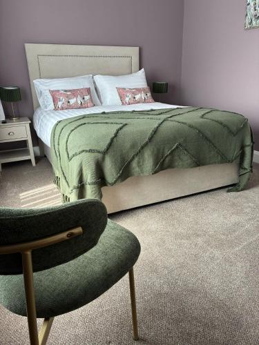 a bedroom with a bed with a green blanket and a chair at The Monks Quarters in Quin