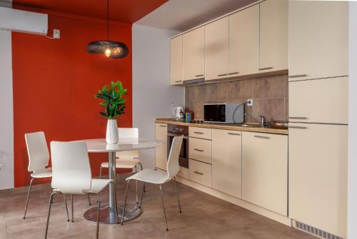 a kitchen with white cabinets and a table with white chairs at Full Sea View Penthouse with Panoramic terrace in Prčanj