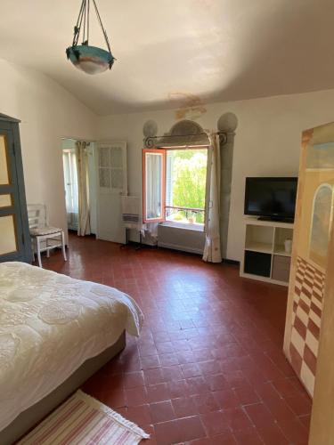 a bedroom with a bed and a television and a room at Syrius - Logement d'artiste avec terrasse et vue in Fontaine-de-Vaucluse