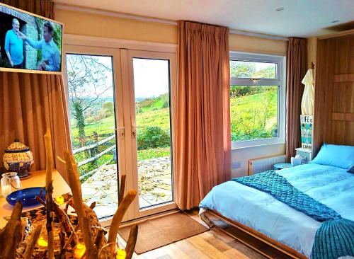 a bedroom with a bed and a large window at Sea Moss Cabin in Tywyn