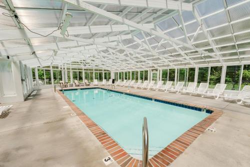 a large swimming pool with white chairs in a building at Sleepy Bear Getaway condo in Pigeon Forge