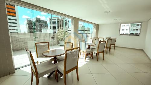 a dining room with tables and chairs and a large window at Lorenzo Di Credi Tambaú Genius Flats in João Pessoa