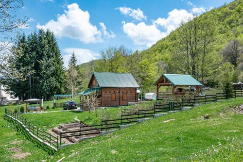 a group of wooden buildings on a grassy hill at Private Cabin in the Woods in Žabljak