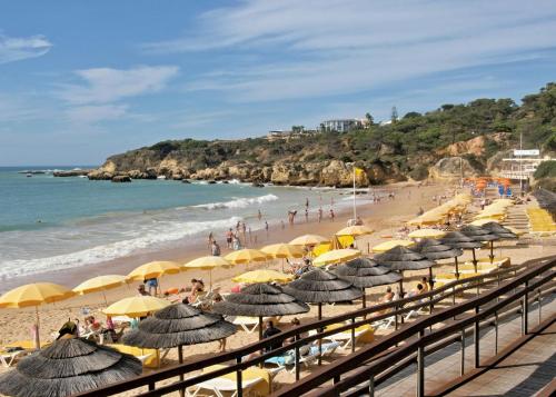 a beach with yellow umbrellas and people on the sand at Oura Oasis F by Check-in Portugal in Albufeira