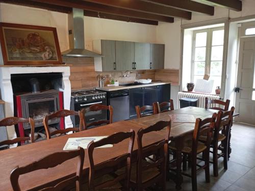 une cuisine avec une grande table et des chaises en bois dans l'établissement La Maison de la Guérande, à Hénanbihen