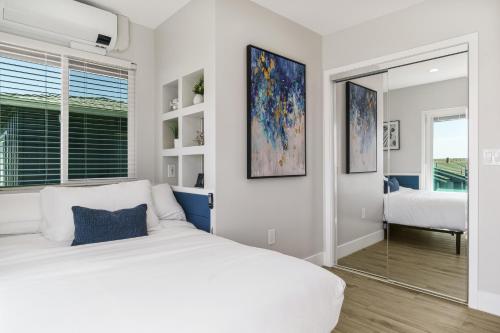 a white bedroom with a bed and a mirror at Tower 9 in Oceanside