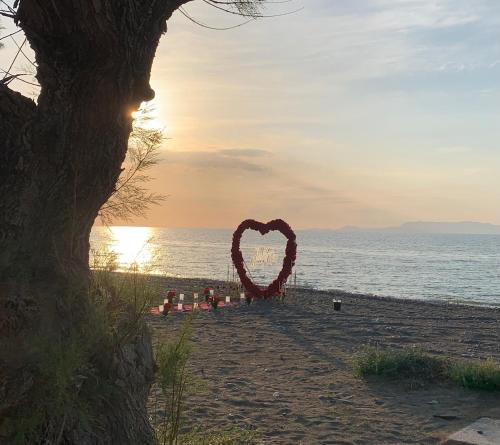 a heart shaped sign on a beach with the sunset at Alkyonides Boutique Hotel in Kremasti
