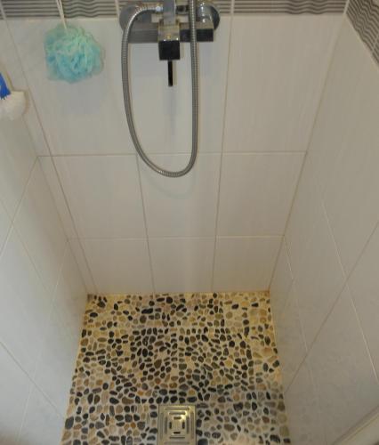 a bathroom with a shower with a tiled floor at La Cadanise, Suite Étoilée in Saint-Éloy-les-Mines