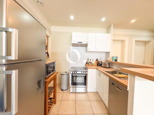a kitchen with white cabinets and a stainless steel refrigerator at COC - Au Vent Du Kent in Wissant