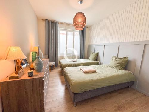 a bedroom with two beds and a table with a lamp at COC - Au Vent Du Kent in Wissant