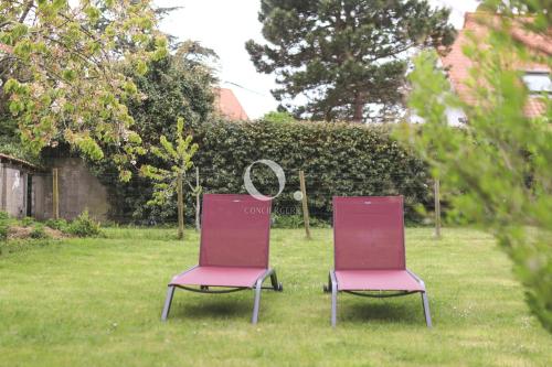 two chairs sitting in the grass in a yard at COC - Au Vent Du Kent in Wissant
