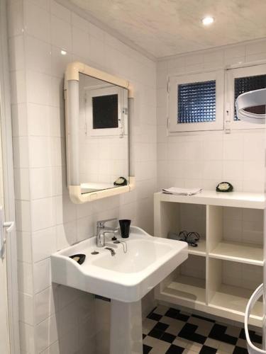 une salle de bain blanche avec un lavabo et un miroir dans l'établissement Appartement Coutain face Mer, à Agon-Coutainville