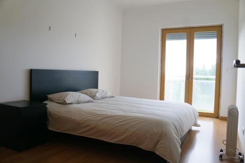 a bed in a bedroom with a large window at Vista Gama in Santa Iria da Azóia