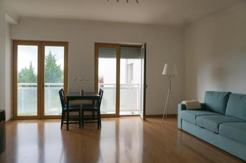 a living room with a blue couch and a table and chairs at Vista Gama in Santa Iria da Azóia