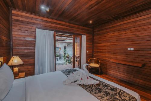 a bedroom with a bed with wooden walls and a window at Kubu Semer Badung in Nusa Lembongan