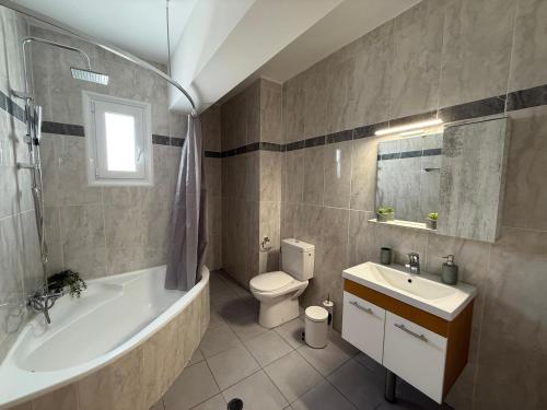 Un baño con bañera, inodoro y lavabo. en Azure Dreams Villa with pool - Haraki beach, en Charaki