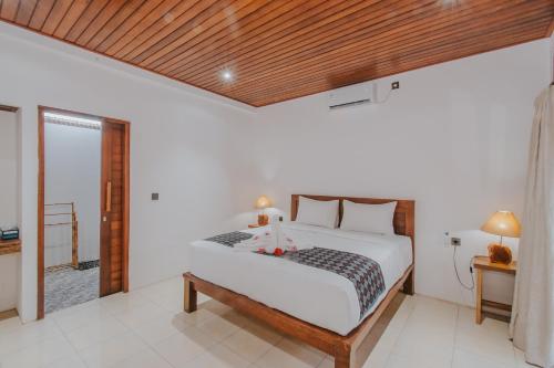 a bedroom with a bed with a wooden ceiling at Kubu Semer Badung in Nusa Lembongan