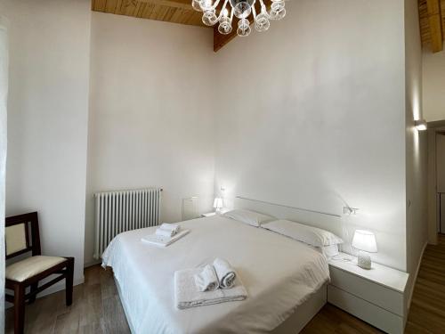 a white bedroom with a bed and a chandelier at Casa Manzoni Gravedona - Larihome A84 in Gravedona