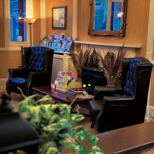 a waiting room with chairs and a table and a fireplace at The Robin Hill in Torquay