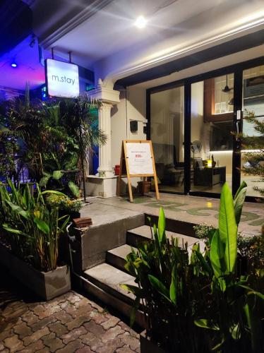 a sign on the side of a building with plants at mstay in Bangkok