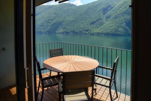 a table and chairs on a balcony with a view of a lake at Unique Gandria Attic by Quokka 360 - Elegant Lake View Apartment in Lugano