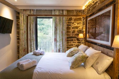 ein Schlafzimmer mit einem Bett mit Kissen und einem Fenster in der Unterkunft Ribeira Sacra a Orilla Rio Miño Casas do Pincelo in Pincelo