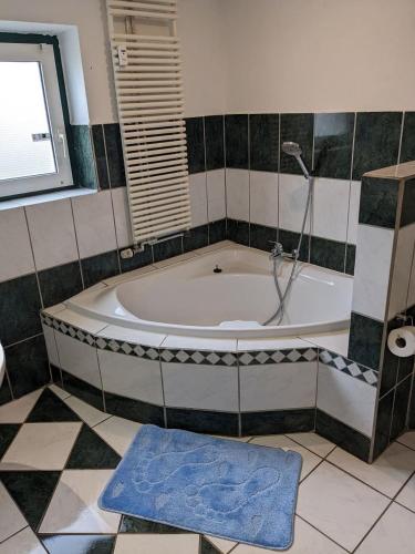 a bathroom with a tub with a shower and a blue rug at Große Landhauswohnung in Ramhusen