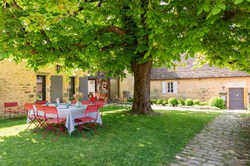 a table and chairs under a tree in a yard at Les Hauts de Saint Vincent B&B proche Sarlat in Saint-Vincent-de-Cosse