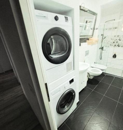 a washing machine in a bathroom next to a toilet at Apartament 3 Cam Hd in Hunedoara