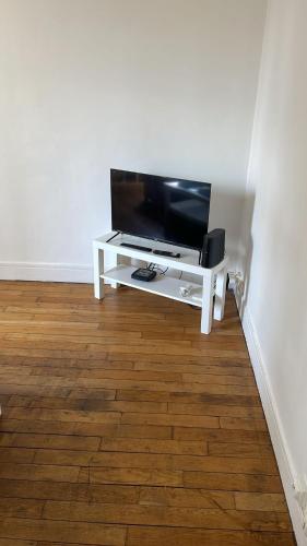 un salon avec une télévision sur une table blanche dans l'établissement Appartement proche Roland Garros, à Boulogne-Billancourt