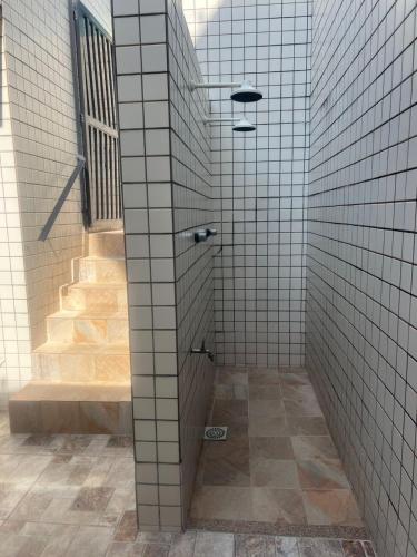 a bathroom with white tile walls and a staircase at Aconchego no Canto do Forte - Ar Condicionados - Tvs Grandes - Wi-fi e Estacionamento Incluso! in Praia Grande
