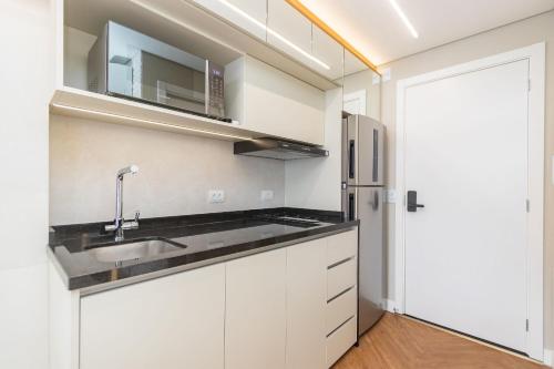 eine Küche mit weißen Schränken und einer Spüle in der Unterkunft Studio no All Batel com Cama Articulada - BAT1805 in Curitiba