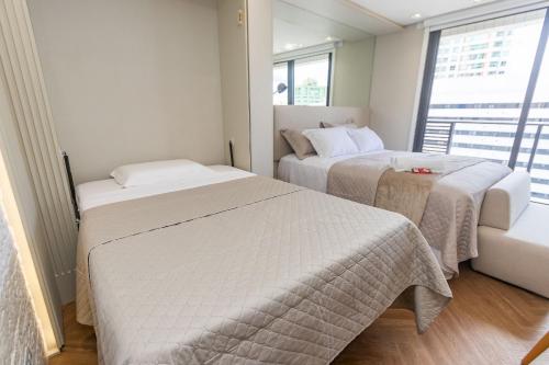 zwei Betten in einem kleinen Zimmer mit Fenster in der Unterkunft Studio no All Batel com Cama Articulada - BAT1805 in Curitiba