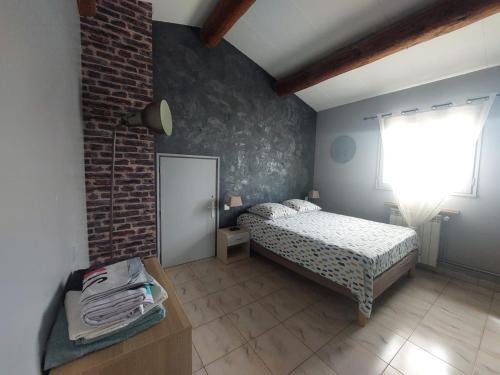 une chambre avec un lit et un mur de briques dans l'établissement Maison familiale avec piscine, à Châteauneuf-du-Pape