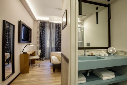 Un baño con lavabo y una cama en una habitación. en Flâneur Suites Corso, en Roma