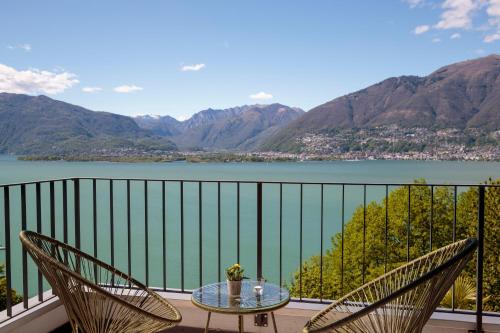 a balcony with chairs and a table and a view of a lake at Bellavista Swiss Quality Hotel in Vira
