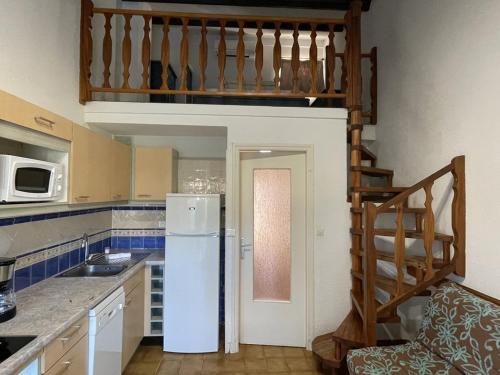 une cuisine avec un réfrigérateur blanc et un escalier dans l'établissement VILLA 6 personnes Heliovillage HV45 -, au Cap d'Agde