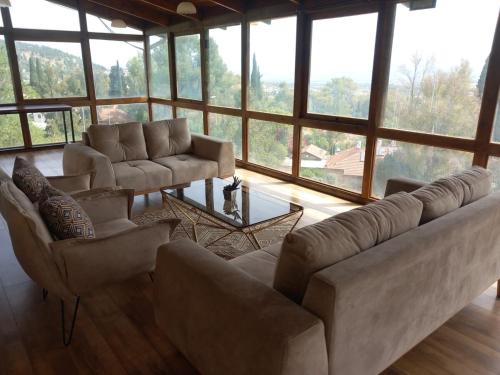 a living room with couches and chairs and a large window at אחוזת שולמית דירה 5 in Rosh Pinna
