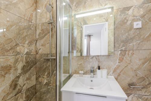 une salle de bain avec un lavabo et une douche avec un miroir dans l'établissement Nid douillet pour deux cœur du 19e arrondissement, à Paris